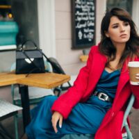 stylish woman in red coat sitting in cafe