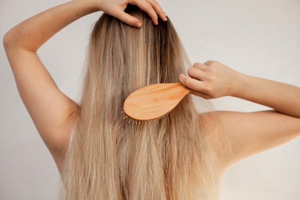 Female combing her blond hair with a wooden comb